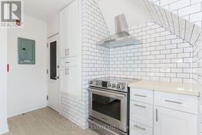 Toronto (High Park-Swansea) multi-family for rent - A kitchen with white cabinets and a black and white tiled backsplash.