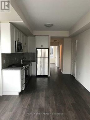 Toronto (Briar Hill-Belgravia) townhouse for rent - A kitchen with white cabinets and black countertops.