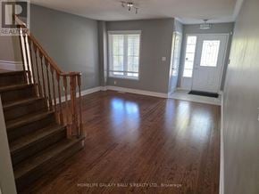 Ajax (Northeast Ajax) apartment for rent - A spacious room with wooden floors and a staircase leading to the upper level.