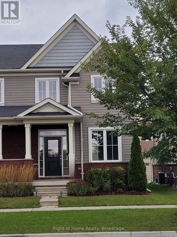 Clarington (Bowmanville) townhouse for rent - A house with a black front door and a tree in front of it.