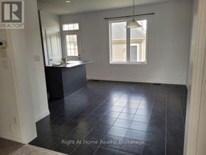 Clarington (Bowmanville) townhouse for rent - A room with a black tile floor and a window with a view of a house.