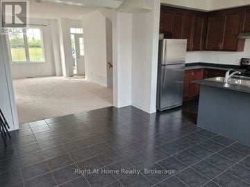 Clarington (Bowmanville) townhouse for rent - A kitchen with a refrigerator, sink, and cabinets.