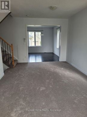 Clarington (Bowmanville) townhouse for rent - A spacious room with a carpeted floor and a staircase leading to the next level.