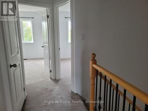 Clarington (Bowmanville) townhouse for rent - A hallway with a carpeted floor and a wooden railing.