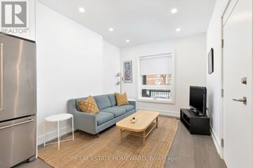Toronto (Trinity-Bellwoods) duplex for rent - A modern living room with a grey couch and a wooden coffee table.