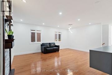 London North (North C) apartment for rent - A spacious living room with a black leather sofa and wooden flooring.