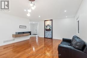 London North (North C) apartment for rent - A spacious living room with a black leather couch and wooden flooring.