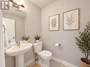 Niagara Falls (Cherrywood) townhouse for rent - A bathroom with a white toilet, sink, and two framed leaves on the wall.
