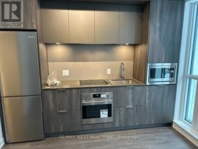 Toronto (Regent Park) condo for rent - A modern kitchen with a stainless steel refrigerator and wooden cabinets.