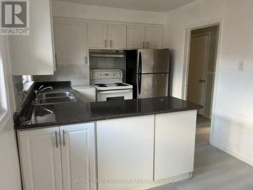 Toronto (Tam O'shanter-Sullivan) apartment for rent - A kitchen with white cabinets and a black countertop.