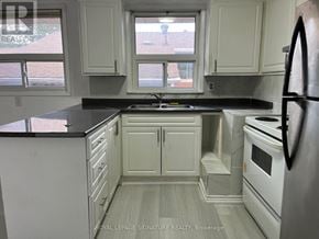 Toronto (Tam O'shanter-Sullivan) apartment for rent - A kitchen with white cabinets and black countertops.