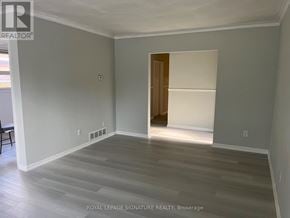 Toronto (Tam O'shanter-Sullivan) apartment for rent - A room with grey walls and wooden flooring, with a doorway leading to another room.