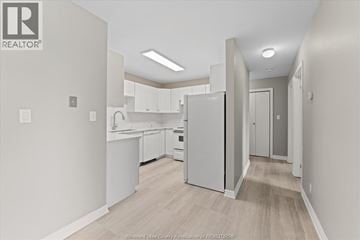 Leamington condo for rent - A kitchen with white appliances and cabinets in a real estate listing.