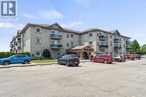Leamington condo for rent - A blue car is parked in front of a building with the REALTOR® logo.