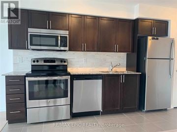 Toronto (Yorkdale-Glen Park) condo for rent - A kitchen with brown cabinets and a white refrigerator.