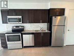 Toronto (Yorkdale-Glen Park) condo for rent - A kitchen with brown cabinets and a stainless steel refrigerator.