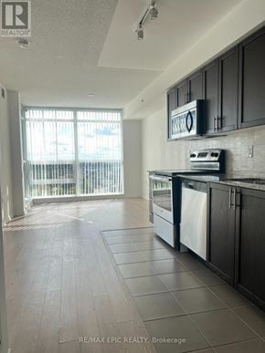 Toronto (Yorkdale-Glen Park) condo for rent - A kitchen with black cabinets and a white fridge.
