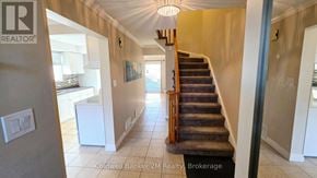 Oshawa (Pinecrest) apartment for rent - A hallway with a staircase and a light switch on the wall.