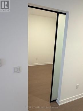Toronto (Forest Hill South) condo for rent - A white wall with a switch and a doorway leading to another room.