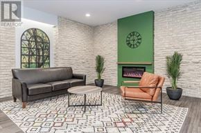 Guelph (Willow West/Sugarbush/West Acres) condo for rent - A living room with a grey couch, a green fireplace, and a patterned rug.