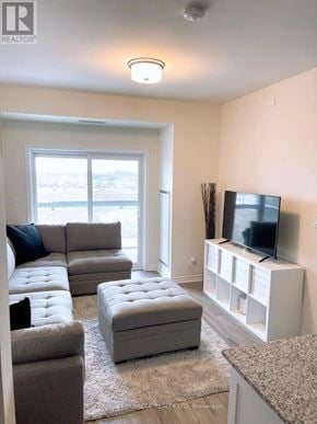 Brampton (Northwest Brampton) condo for rent - A living room with a grey couch, ottoman, and a television on a white stand.