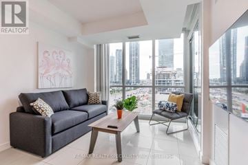 Mississauga (City Centre) condo for rent - A living room with a grey couch, a coffee table, and a painting of flamingos.
