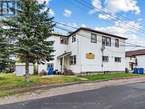 East Gwillimbury (Holland Landing) multi-family for rent - A white two-story house with a brown roof and a sign that says "Highgate Property Investments Brokerage Inc." on the front.