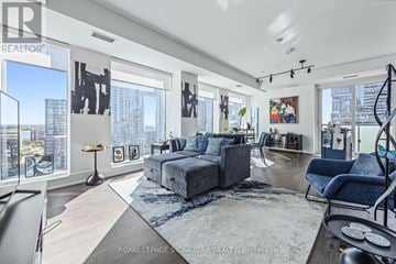 Toronto (Waterfront Communities) condo for rent - A spacious living room with a grey sofa set and a large window overlooking the city.