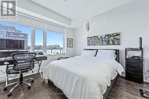 Toronto (Waterfront Communities) condo for rent - A bedroom with a large bed, a desk with a chair, and a window overlooking the city.