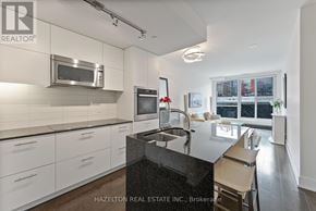 Toronto (Annex) condo for rent - A modern kitchen with white cabinets and a black countertop.