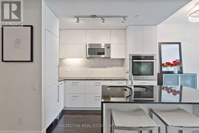 Toronto (Annex) condo for rent - A modern kitchen with white cabinets and stainless steel appliances.