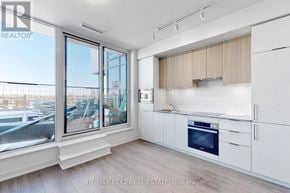 Toronto (Banbury-Don Mills) condo for rent - A kitchen with white cabinets and a large window overlooking a parking lot.