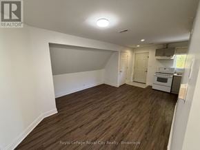 Guelph (Exhibition Park) apartment for rent - A room with wooden flooring and white walls, with a kitchen area visible in the background.