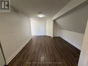 Guelph (Exhibition Park) apartment for rent - A room with wooden flooring and white walls, with a logo for Royal LePage Royal City Realty, Brokerage in the bottom left corner.