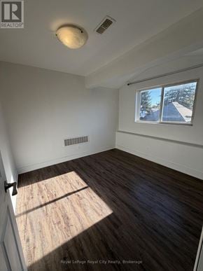 Guelph (Exhibition Park) apartment for rent - A room with wooden flooring and a window showing a view of a house.