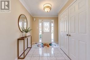 Brampton (Heart Lake West) apartment for rent - A hallway with a round mirror, a plant, and a vase on a wooden stand.