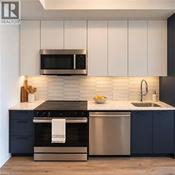 Kitchener condo for rent - A modern kitchen with a stainless steel oven and microwave above a sink.