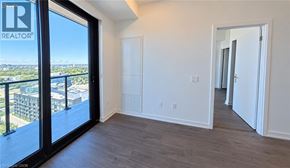 Kitchener condo for rent - A room with a sliding glass door leading to a balcony with a view of the city.