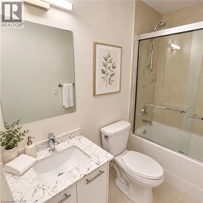 Kitchener condo for rent - A white bathroom with a marble counter top and a toilet.