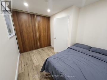 Toronto (Glenfield-Jane Heights) apartment for rent - A bedroom with a bed, wooden wardrobe and a white door.