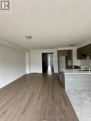 North Dumfries townhouse for rent - A spacious room with wooden flooring and a kitchen area in the background.