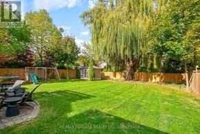 Niagara-On-The-Lake (Town) apartment for rent - A backyard with a lawn, trees, and a wooden fence.