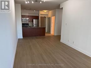 Mississauga (City Centre) condo for rent - A realtor logo is on a pillar in a room with white walls and wood flooring.