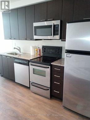 Toronto (Niagara) condo for rent - A kitchen with a stainless steel refrigerator, microwave, oven, and sink.