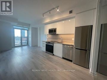 Toronto (Moss Park) condo for rent - A spacious kitchen with white cabinets and stainless steel appliances.