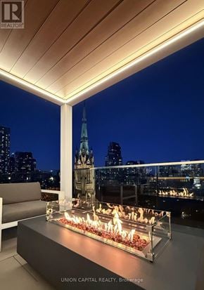 Toronto (Church-Yonge Corridor) condo for rent - A modern outdoor seating area with a fire pit and a view of the city skyline at night.
