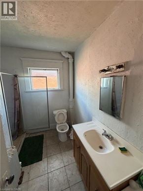 Brantford apartment for rent - A bathroom with a toilet, sink, and mirror.