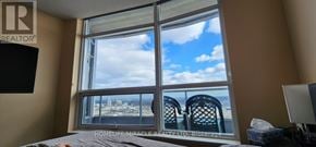 Toronto (Agincourt South-Malvern West) condo for rent - A bedroom with a large window overlooking a cityscape.