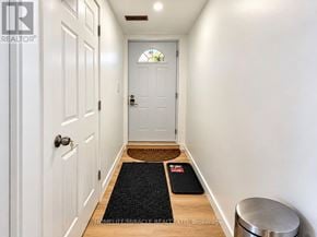 Guelph (Kortright Hills) apartment for rent - A hallway with a white door, a black mat on the floor, and a stainless steel trash can.