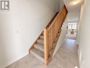 Haldimand townhouse for rent - A staircase with wooden railings and a beige carpeted runner.